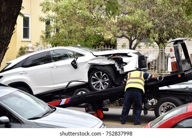 A Tow Truck Driver Loading A Wrecked Car Onto A Tow Truck