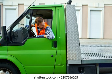 Tow Truck Driver Transporting Car Down Street