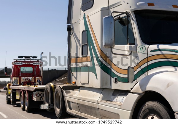 A tow\
truck drives a broken truck down the\
highway