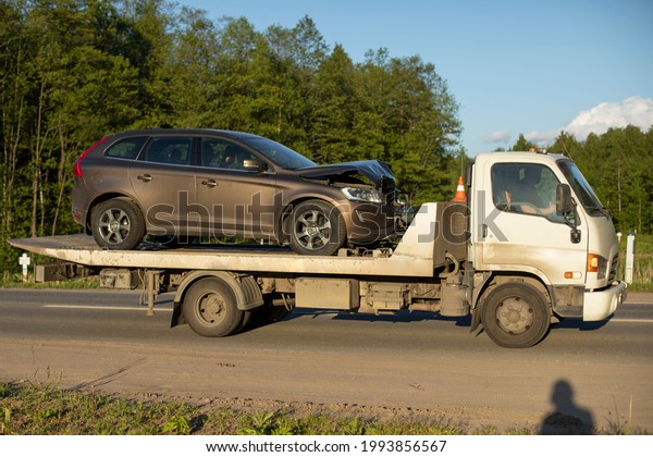 A tow truck is driving a car after an accident.\
Car transportation on a cargo platform. The loader takes away the\
emergency vehicle.