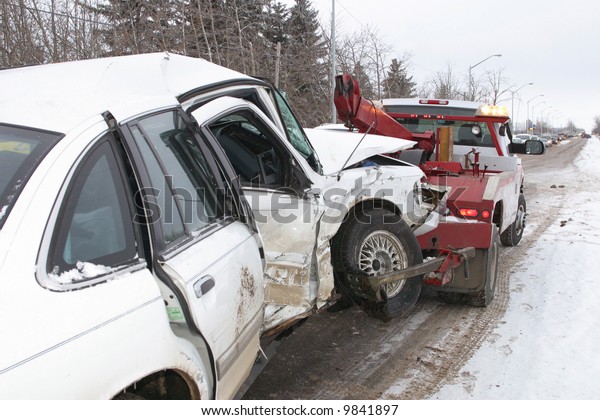 A tow\
truck hauls away a car from an accident\
scene.