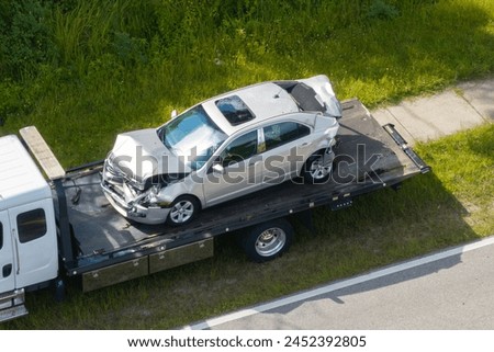 Tow truck loading crashed car on accident site. Emergency services personnel and vehicles responding to vehicle crash on American street. First responders helping on road in the USA.