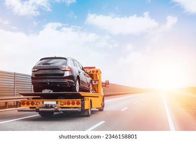 A tow truck on the public road. Tow truck with broken car on country road. Tow truck transporting car on the highway. Car service transportation concept.