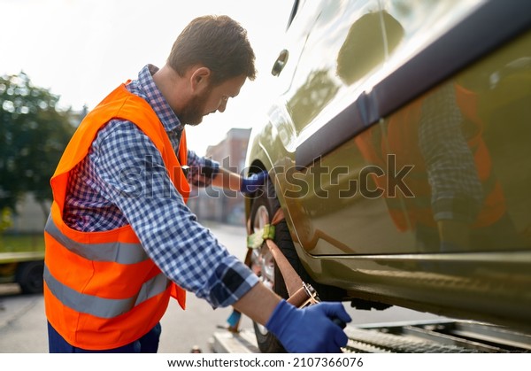 Tow truck operator\
fixing car on platform
