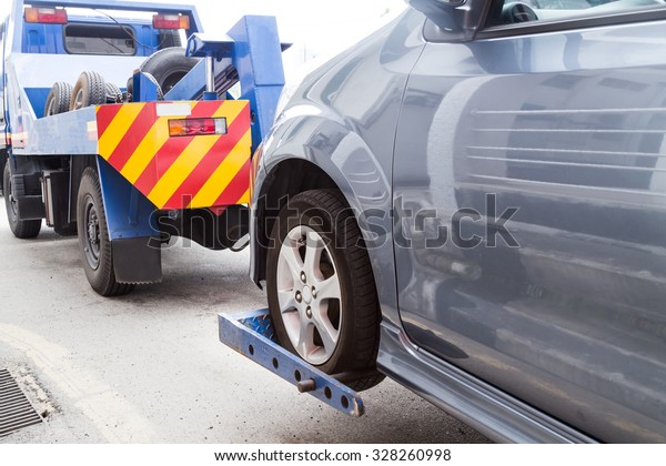 Tow truck\
towing a broken down car on the\
street.