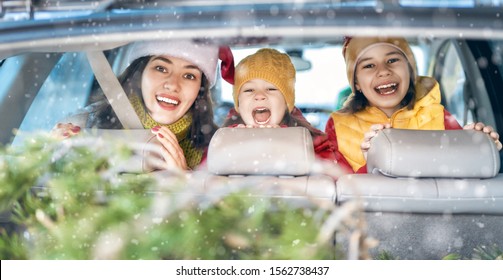 Toward Adventure! Happy Family Are Relaxing And Enjoying Road Trip. Mother, Children And Car On Snowy Winter Nature Background. Christmas Holidays Time.