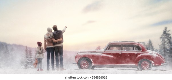 Toward adventure! Happy family relaxing and enjoying road trip. Mom, dad, child and vintage car on snowy winter nature background. Christmas holidays time.