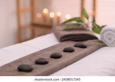 Towel with arranged spa stones on massage table in recreational center, closeup - Powered by Shutterstock