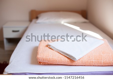 Towel and bedding on a single bed in hostel or guest house room, no reservations guests or visitors, empty no people due to outbreak of deadly Coronavirus (COVID-19) global pandemic crisis, cancelled 