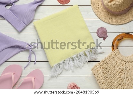 Towel and different beach items on white wooden background, flat lay