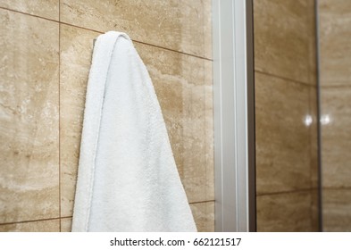 a towel hanging on a hook in the bathroom on the background of a marble wall - Powered by Shutterstock