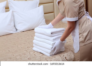 Towels in the hands of the maid. Unrecognizable photo without a face. Cleaning the hotel room. Copy space. The concept of the hotel business. - Shutterstock ID 1693313614