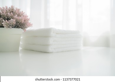 Handtücher auf weißem Holztisch mit Kopienraum auf unscharfem Badhintergrund. Montag für die Produktanzeige
