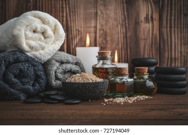 Towels With Sea Salt, Massage Oil In Vintage Bottle, Candles And Stones For Stone Massage On Wooden Background