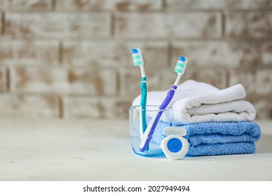 Towels, Tooth Brushes And Floss On Table In Bathroom