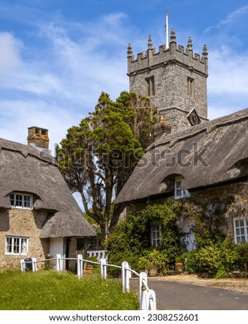 The tower of All Saints Church and beautiful thatched cottages in the picturesque village of Godshill on the Isle of Wight, UK.