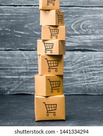 Tower Of Cardboard Boxes With Pattern Of Shopping Carts On A Blue Background. Commerce, Online Shopping. Purchasing Power, Delivery Order. E-commerce, Logistics, Distribution And Sales.