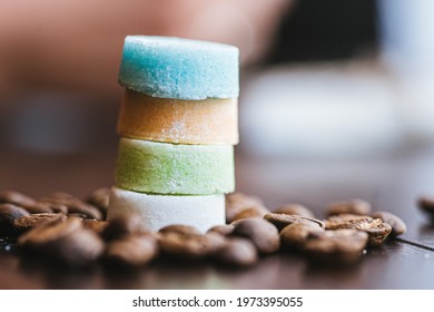 Tower Of Colored Round Sugar Cubes Among Coffee Beans On Wooden Surface