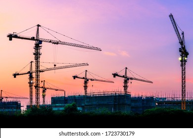 Tower Crane And Building Construction Site Silhouette At Sunrise.