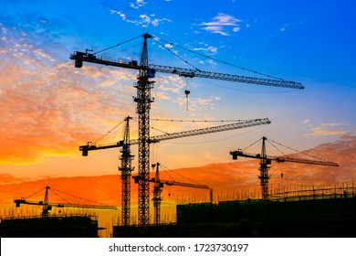 Tower crane and building construction site silhouette at sunrise.