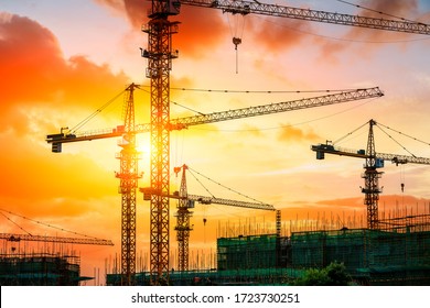 Tower Crane And Building Construction Site Silhouette At Sunrise.