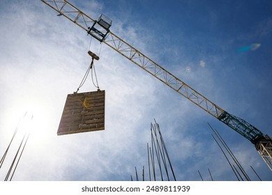 Tower crane is carry, transport peace of large demountable mold high over building site. - Powered by Shutterstock