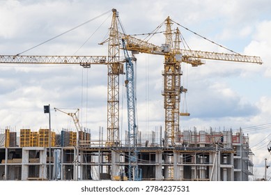 Tower cranes actively constructing a modern residential building, featuring intricate scaffolding and formwork, representing continuous urban development and architectural progress