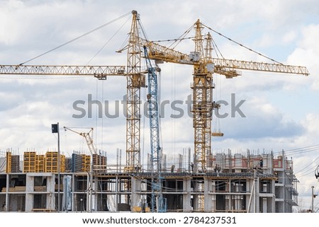 Tower cranes actively constructing a modern residential building, featuring intricate scaffolding and formwork, representing continuous urban development and architectural progress