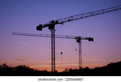 Tower Cranes At Evening Red Pruple Light In A Construction Site In Budapest Suburb, Hungary