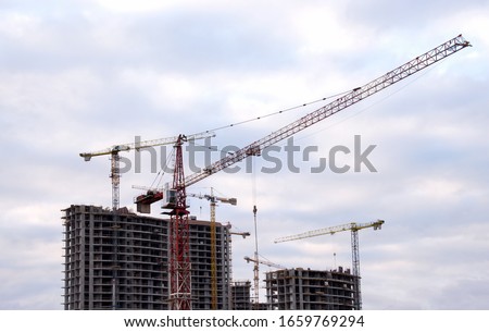 Tower cranes at large scale construction site against blue sky. Construction crane. Formwork solutions for reinforced construction and framed superstructure. Сoncept of renovation of new housing