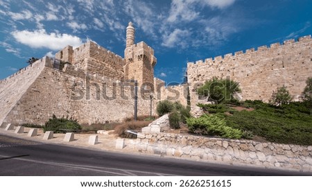 Tower of David timelapse hyperlapse and Old Town wall in Jerusalem, Israel. Traffic on a road. Blue sky