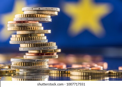 Tower with euro coins and flag of European Union in the background.