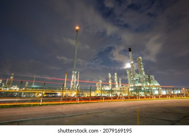 Oil​ refinery​ and tower flare fire of petrochemistry industry in oil​ and​ gas​ ​industry with​ cloud​ blue​ ​sky traffic light road transportation truck the evening​ background​.