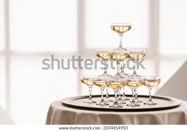 Tower\
made of glasses with champagne on table\
indoors