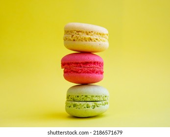 tower of multi-colored assorted bright macarons close-up on yellow background