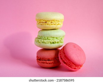 tower of multi-colored assorted bright macarons close-up on light pink background