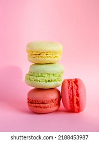 tower of multi-colored assorted bright macarons close-up on light pink background, Stack of four lemon yellow, mint green and pink cookies. Copy spase, side view, vertical