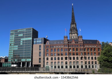 The tower of the St. Nicholas, or Nikolaikirche church above old and modern office buildings in Hamburg, Germany