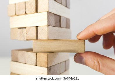The tower from  wooden blocks and man's hand take one block