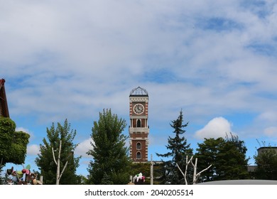 A Towering Brick Clock Tower Seen Through The Trees