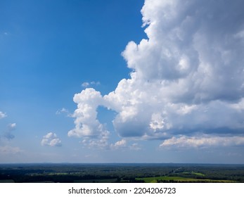 Towering Cumulonimbus Clouds Over Green Rural Landscape With Deep Blue Sky And Negative Space For Copy.