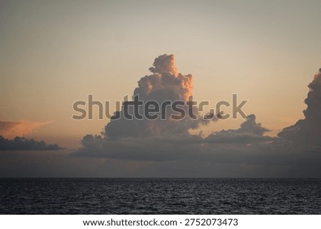 Towering cumulus clouds over ocean at sunset
