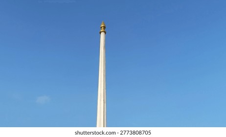 the towering flagpole, blue clouds. 