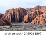 The towering red Navajo sandstone cliffs at Snow Canyon State Park. The breathtaking rock formations rise steeply from the grassy valley below. Taken in the early morning light - St George, Utah, USA