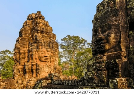 Towers and three of the 216 smiling sandstone faces at 12th century bayon temple in angkor thom walled city, angkor, unesco world heritage site, siem reap, cambodia, indochina, southeast asia, asia