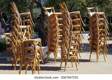 Towers Of Wooden Chairs Stacked Up After A Large Outdoor Event In A Garden Setting