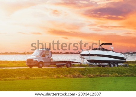 Towing a new motor boat on the road amidst the beautiful sunset in marina bay. Luxury rich fishing leisure recreation lifestyle. Service maintenance transportation.