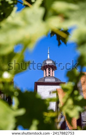 Town hall tower with carillon in the historic old town of Heppenheim in southern Germany seen through a wreath of leaves
