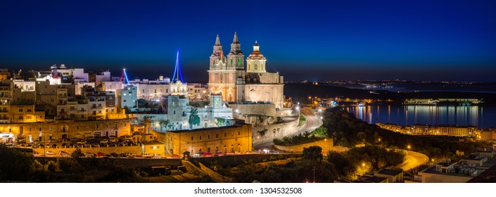 The Town Of Mellieha In The North Of Malta, Shimmers At Blue Hour With The Iconic Parish Church In The Foreground And The Bay And Sister Islands In The Background