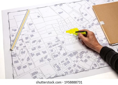 Town Planning And Land Use Planning - Hand Identifying Parcels With A Yellow Marker On A Cadastral Map Placed On A Desk